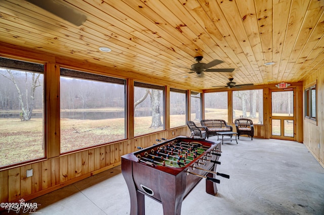 recreation room with wooden walls, wooden ceiling, and ceiling fan