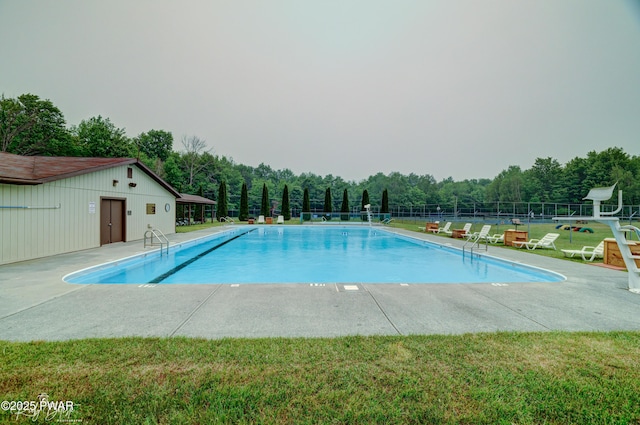 pool featuring a lawn, a patio area, and fence