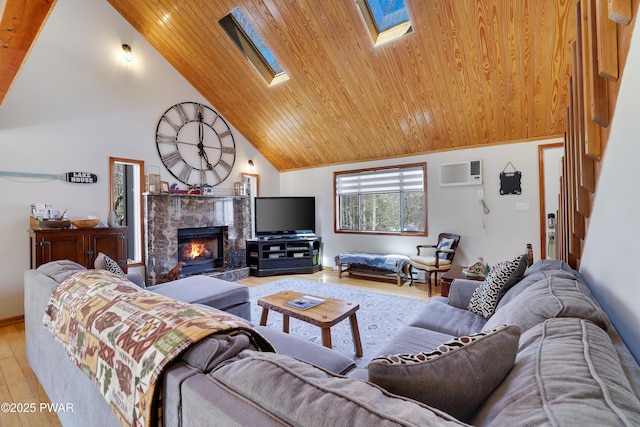 living room with a warm lit fireplace, light wood-style floors, an AC wall unit, wooden ceiling, and a skylight