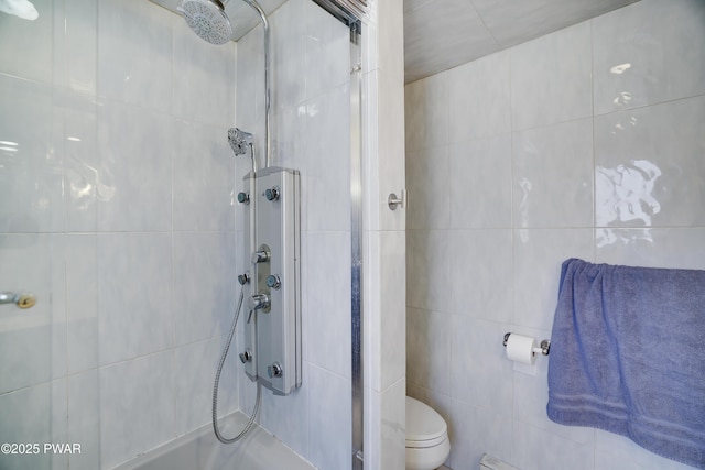 full bathroom with tile walls, toilet, and tiled shower