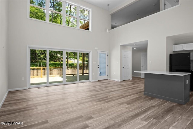 128 Copper Mountain Dr, Tafton, PA 18464 - unfurnished living room with a towering ceiling, plenty of natural light, and light wood-type flooring