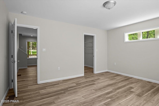 128 Copper Mountain Dr, Tafton, PA 18464 - unfurnished bedroom with light wood-style flooring, multiple windows, a walk in closet, and a closet