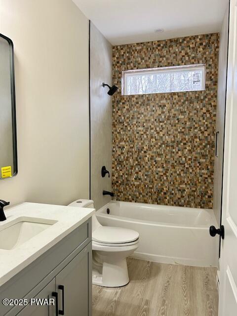 full bathroom with toilet,  shower combination, wood-type flooring, and vanity