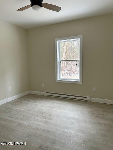 spare room with ceiling fan, a baseboard heating unit, and light hardwood / wood-style flooring