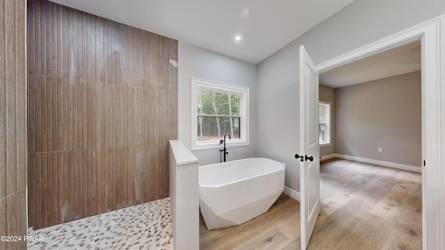 bathroom with shower with separate bathtub and wood-type flooring