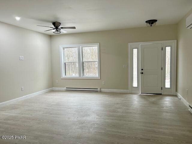 entryway with ceiling fan, a baseboard heating unit, a wall mounted air conditioner, and light hardwood / wood-style floors