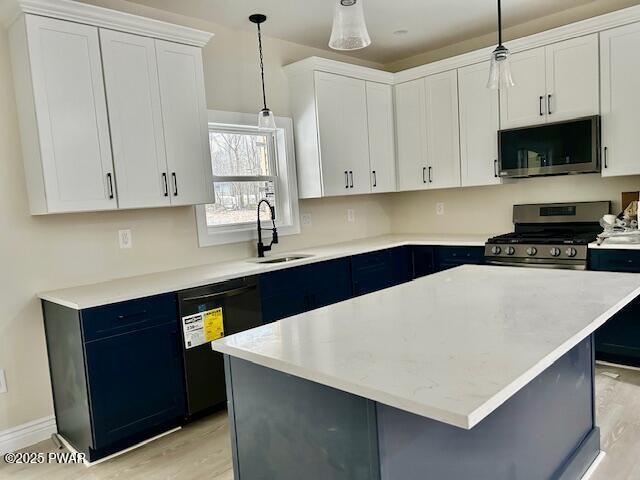 kitchen featuring appliances with stainless steel finishes, a center island, decorative light fixtures, white cabinets, and sink