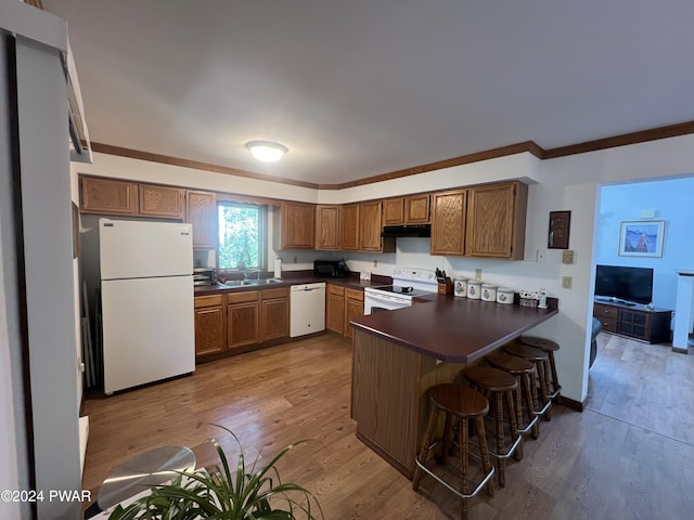 kitchen with a kitchen breakfast bar, kitchen peninsula, white appliances, and light wood-type flooring