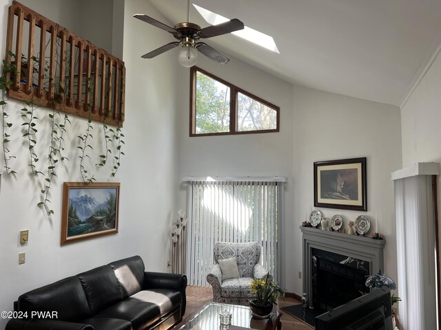 living room with a skylight, ceiling fan, and high vaulted ceiling