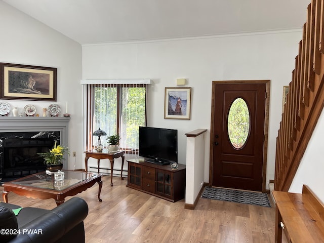 living room featuring light hardwood / wood-style flooring, a high end fireplace, a baseboard radiator, and lofted ceiling