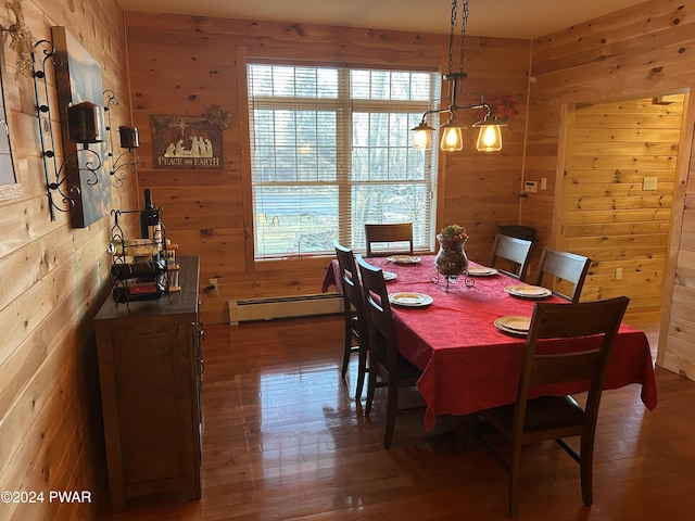 dining space with hardwood / wood-style floors, wood walls, and a baseboard radiator