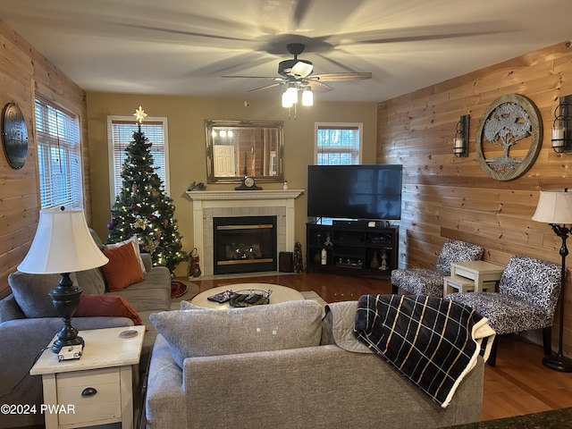 living room with hardwood / wood-style flooring, ceiling fan, a fireplace, and wooden walls