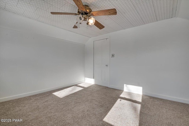 empty room with carpet, vaulted ceiling, baseboards, and ceiling fan