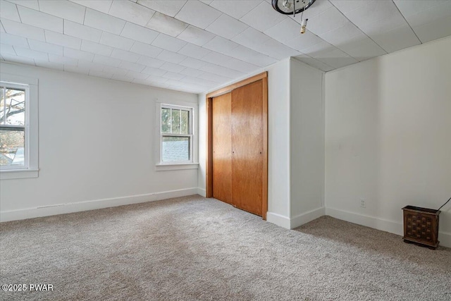 unfurnished bedroom featuring light carpet, baseboards, and a closet