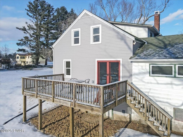 snow covered property featuring roof with shingles, a chimney, stairway, and a wooden deck