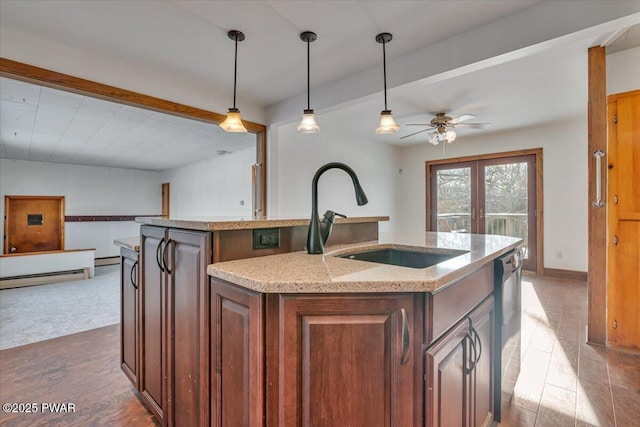 kitchen featuring open floor plan, decorative light fixtures, a kitchen island with sink, french doors, and a sink