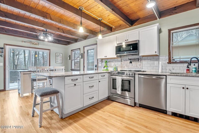 kitchen featuring light stone countertops, stainless steel appliances, sink, beamed ceiling, and white cabinets