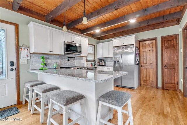 kitchen with appliances with stainless steel finishes, tasteful backsplash, white cabinetry, and light stone counters