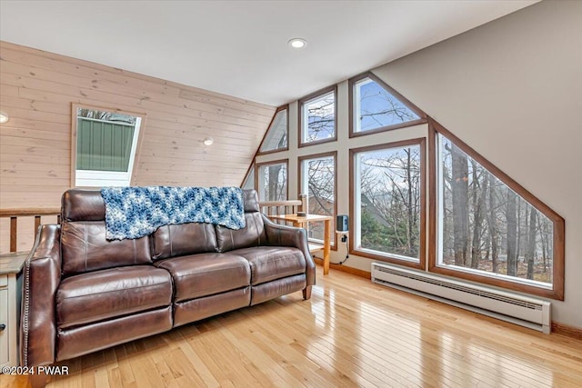 living room with wood walls, light wood-type flooring, and baseboard heating