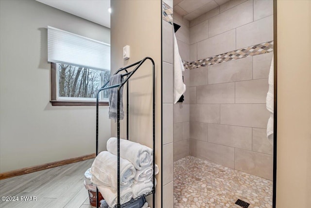 bathroom with tiled shower and hardwood / wood-style flooring