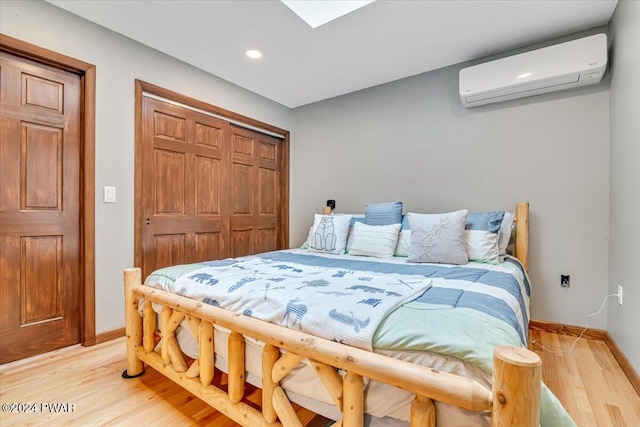 bedroom with light hardwood / wood-style flooring, a wall unit AC, and a closet