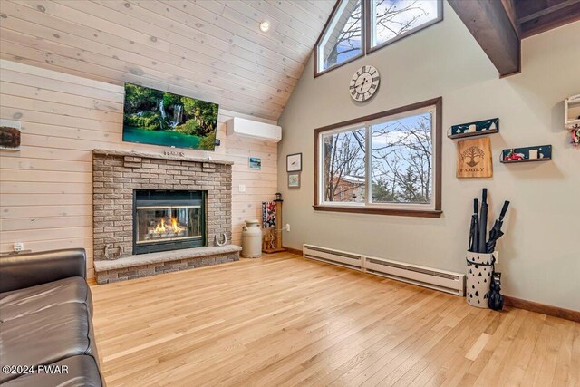 living room with baseboard heating, a fireplace, plenty of natural light, and a wall mounted air conditioner