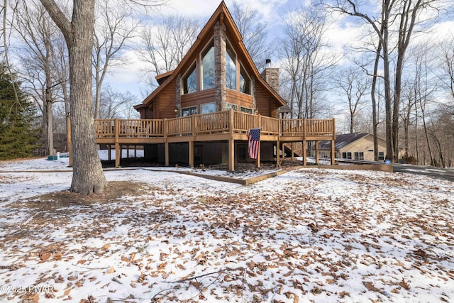 snow covered back of property featuring a wooden deck