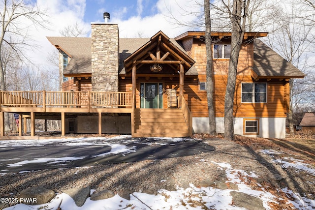 snow covered rear of property with a deck