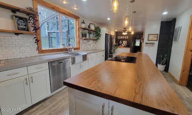 kitchen with appliances with stainless steel finishes, light wood-type flooring, white cabinetry, open shelves, and a sink