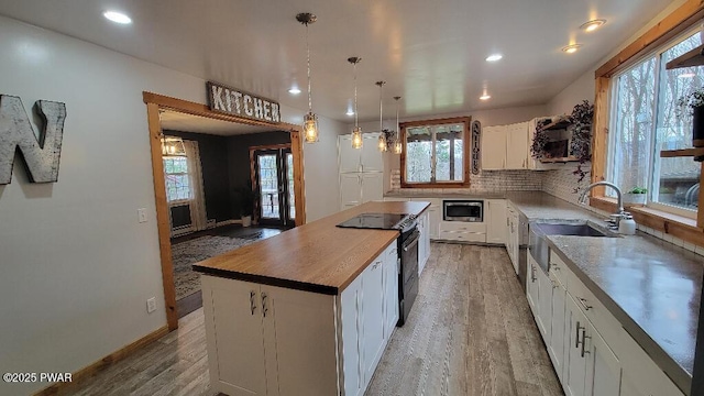 kitchen with backsplash, light wood-style floors, white cabinets, a sink, and black range with electric cooktop