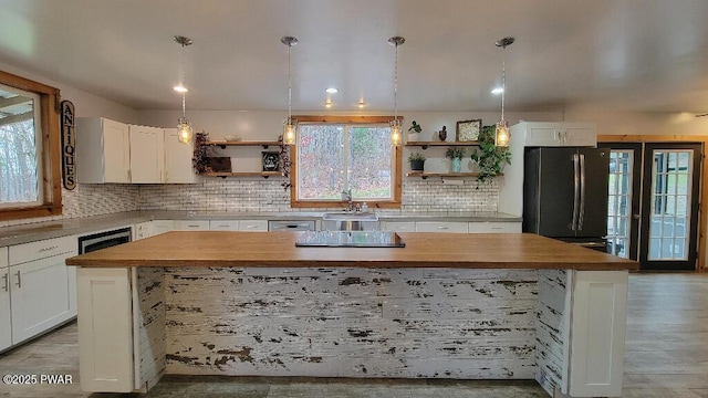 kitchen with black appliances, butcher block counters, open shelves, and a sink