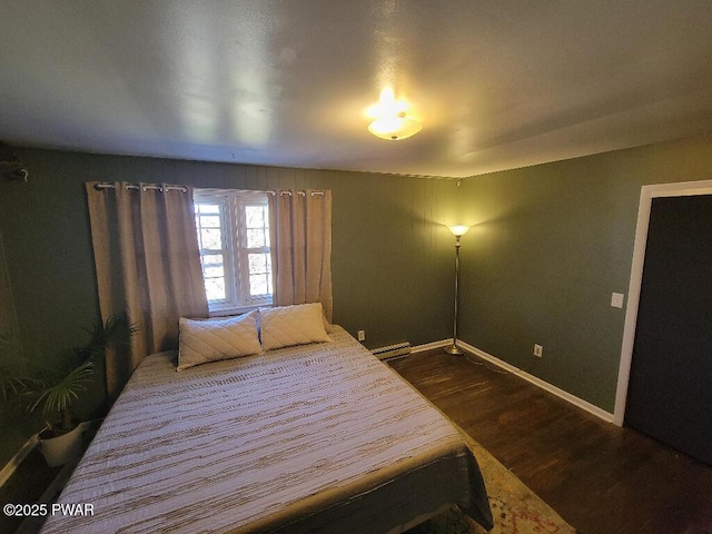 bedroom with baseboard heating, dark wood finished floors, and baseboards