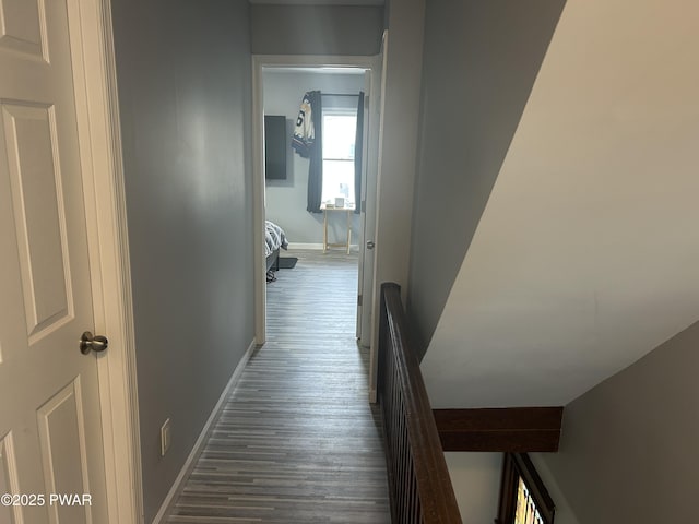 hallway featuring dark wood-style flooring and baseboards