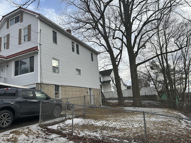 view of snow covered exterior with a fenced front yard and a chimney