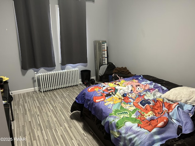 bedroom with radiator heating unit, wood finished floors, and baseboards