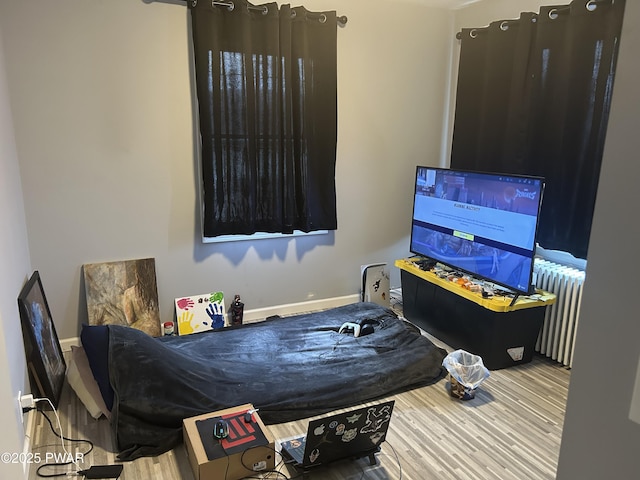 bedroom with radiator, baseboards, and wood finished floors