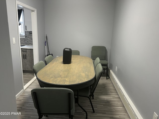 dining room with a baseboard radiator, baseboards, and wood finished floors