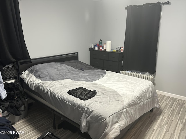 bedroom featuring baseboards, wood finished floors, and radiator