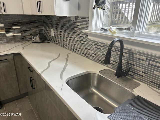 kitchen featuring white cabinetry, a sink, and light stone countertops