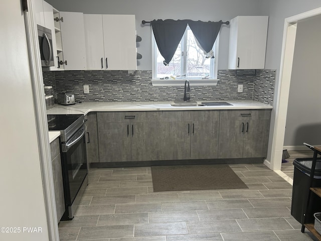 kitchen featuring a sink, light countertops, electric range oven, open shelves, and stainless steel microwave