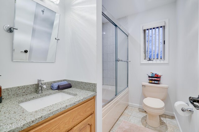 bathroom featuring baseboards, enclosed tub / shower combo, toilet, and vanity