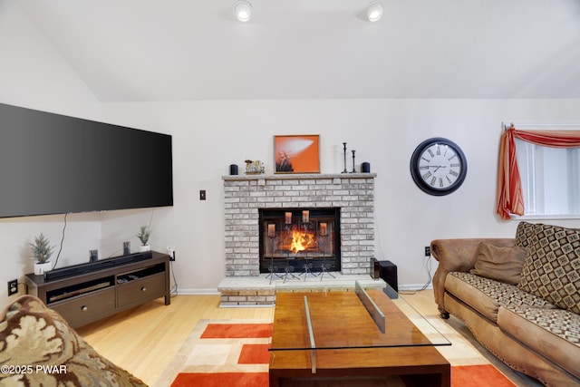 living room with light wood-style flooring, a brick fireplace, baseboards, and vaulted ceiling