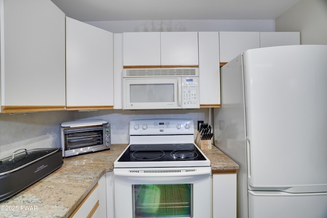 kitchen with a toaster, white appliances, white cabinetry, and light stone countertops