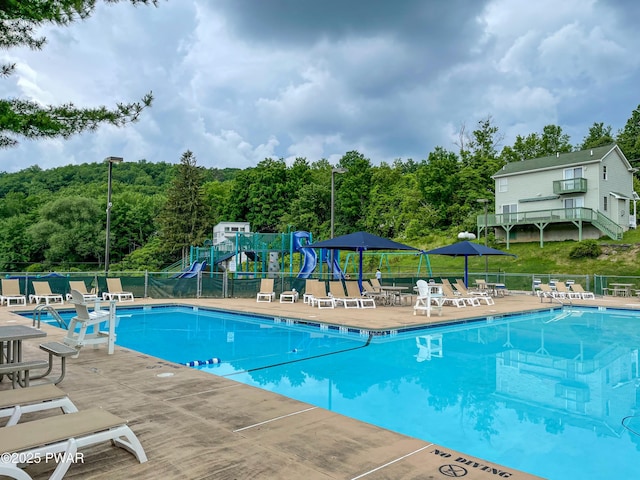 pool with a patio, fence, and playground community