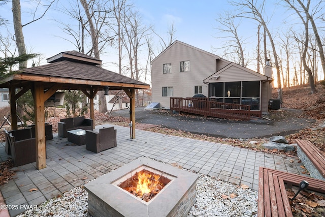 view of patio with an outdoor living space with a fire pit, a gazebo, central air condition unit, and a sunroom