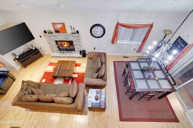 living area with visible vents, a brick fireplace, and wood finished floors