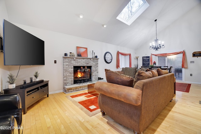 living area with baseboards, light wood-style flooring, a fireplace, an inviting chandelier, and high vaulted ceiling