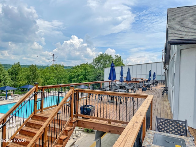 deck featuring outdoor dining area and a community pool