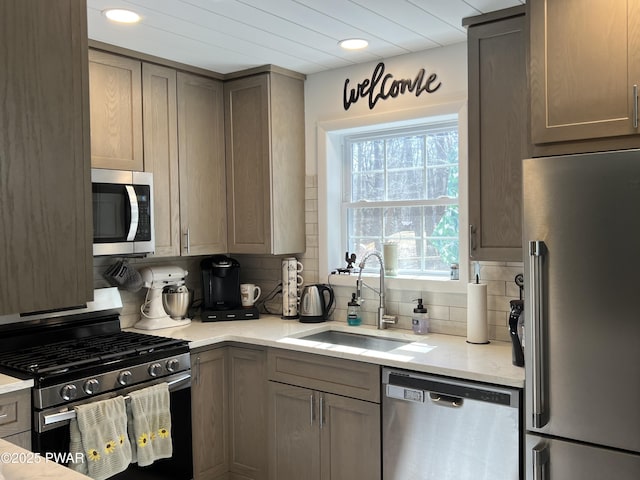 kitchen featuring a sink, tasteful backsplash, recessed lighting, appliances with stainless steel finishes, and light stone countertops