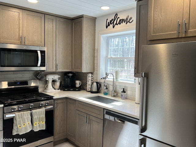 kitchen with recessed lighting, a sink, light countertops, appliances with stainless steel finishes, and backsplash